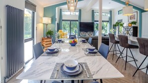 Un espace repas moderne avec une table en marbre, de l’assiette bleue et blanche, et un téléviseur en arrière-plan.