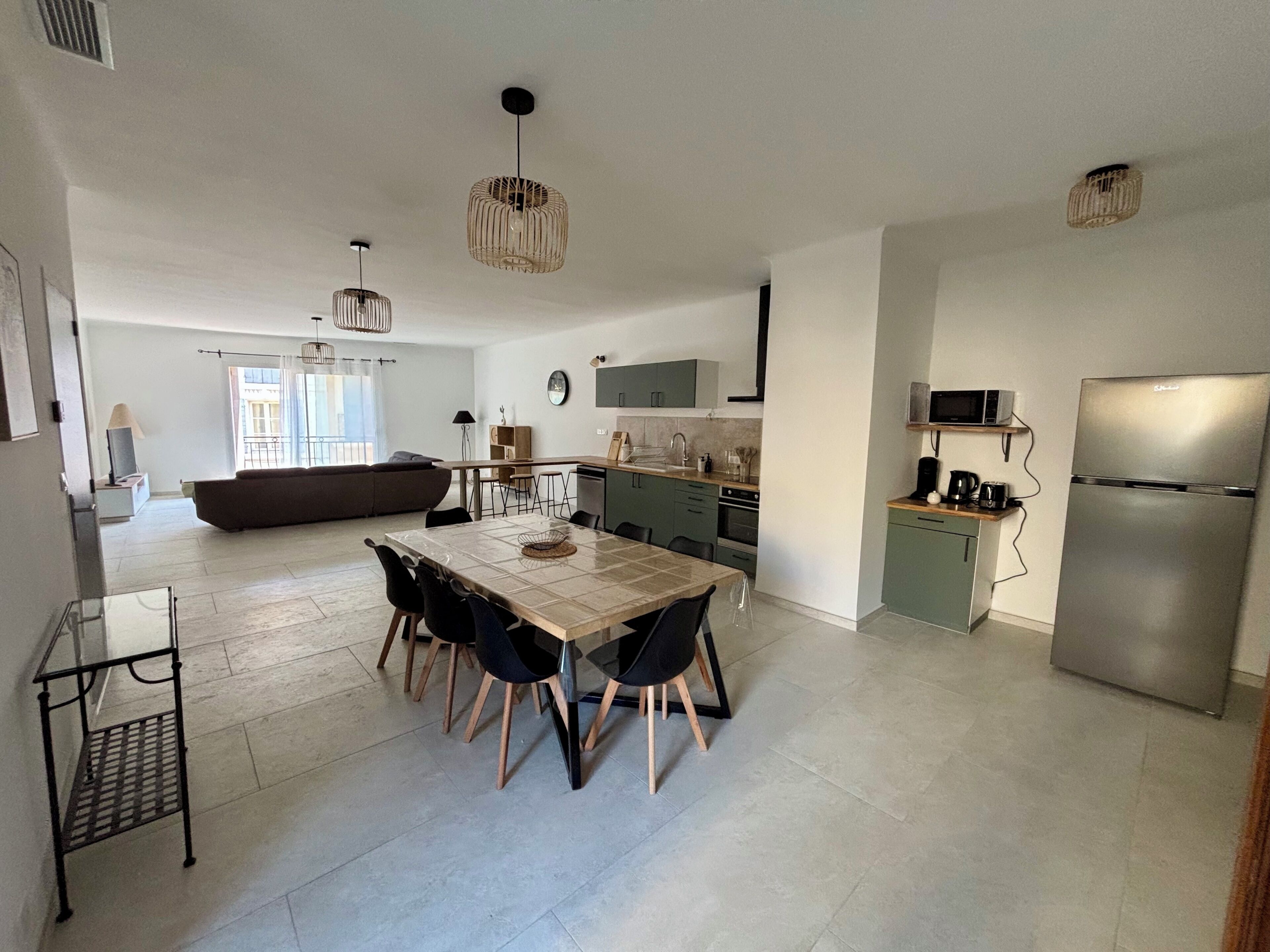 A modern kitchen with a dining area, a built-in oven, and a refrigerator.