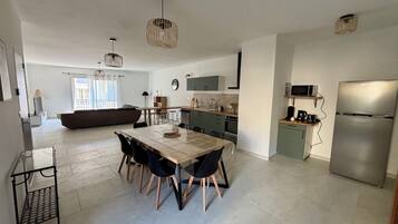 A modern kitchen with a dining area, a built-in oven, and a refrigerator.
