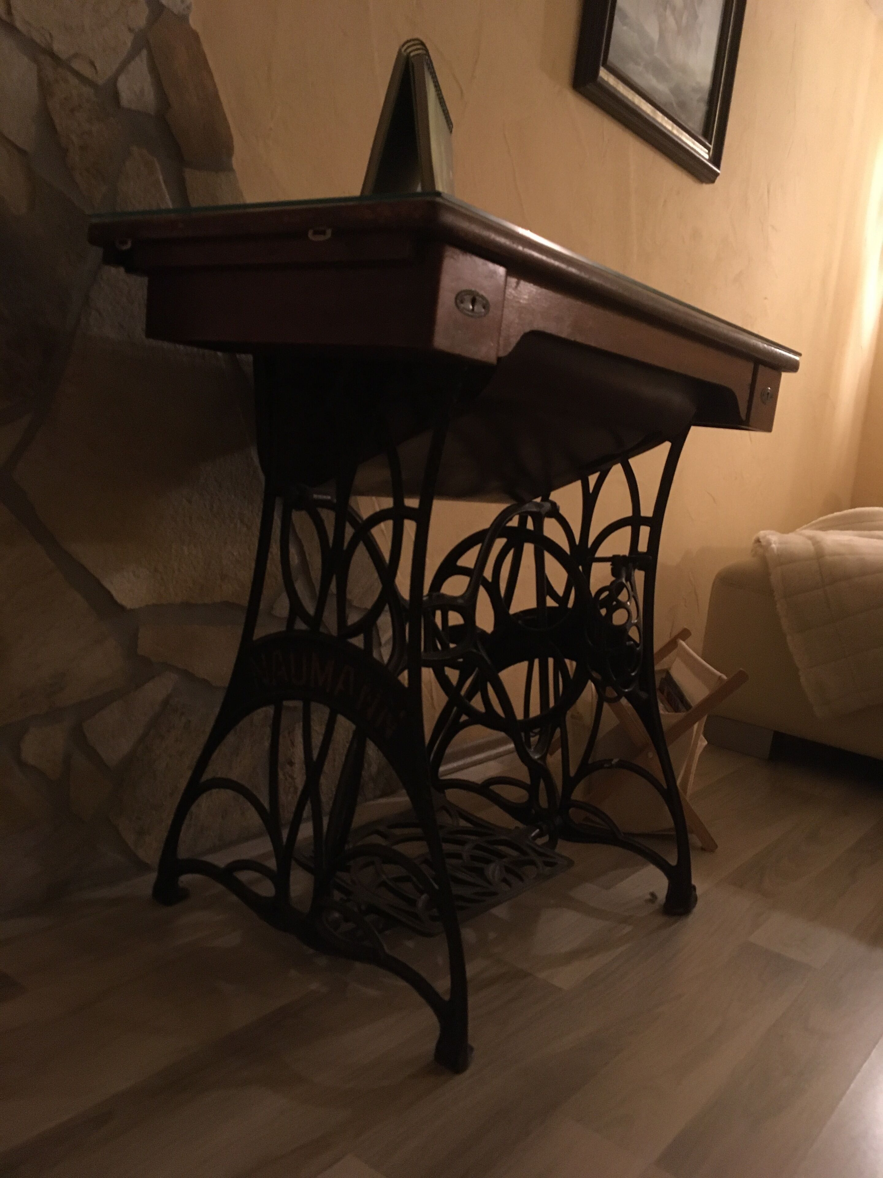 A wooden table with a drawer, black metal legs, and a stone wall in the background.
