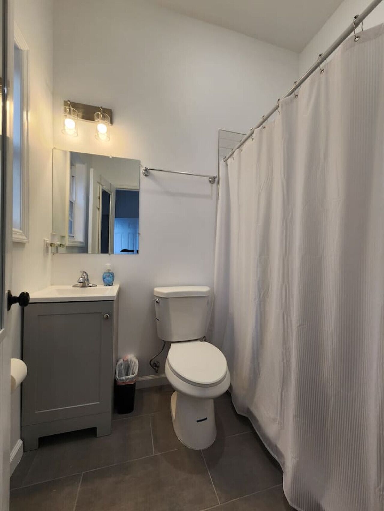 A bathroom with a toilet, sink, and shower curtain.