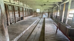 Una habitación larga y estrecha con bancos de madera a lo largo de las paredes y un pasillo central.
