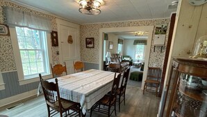 Comedor con una larga mesa, sillas, una araña y un reloj de pared.