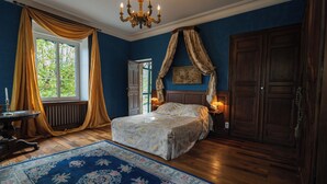 A bedroom with a large bed, a chandelier, a wooden wardrobe, and a window with curtains. - Château privé avec piscine à Cordes-sur-Ciel - Peace, nature and charm-Tarn (Cordes-sur-Ciel)