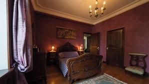 A bedroom with a wooden bed, a nightstand, a bedside table, a chair, and a chandelier. - Château privé avec piscine à Cordes-sur-Ciel - Peace, nature and charm-Tarn (Cordes-sur-Ciel)