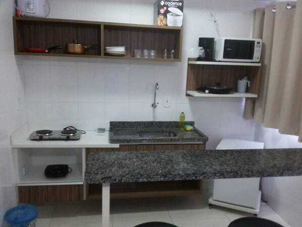A compact kitchen with a granite countertop, a microwave, a stove, and a sink. - Lacqua Di Roma via Roberto Imoveis (Caldas Novas)