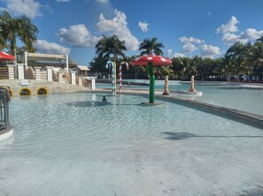 A swimming pool with water slides and decorative umbrellas. - Lacqua Di Roma via Roberto Imoveis (Caldas Novas)