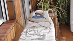 A narrow room with a tiled floor, a small table with a telephone and a charger, and several potted plants. - Los galanes  (Villanueva de los Infantes)