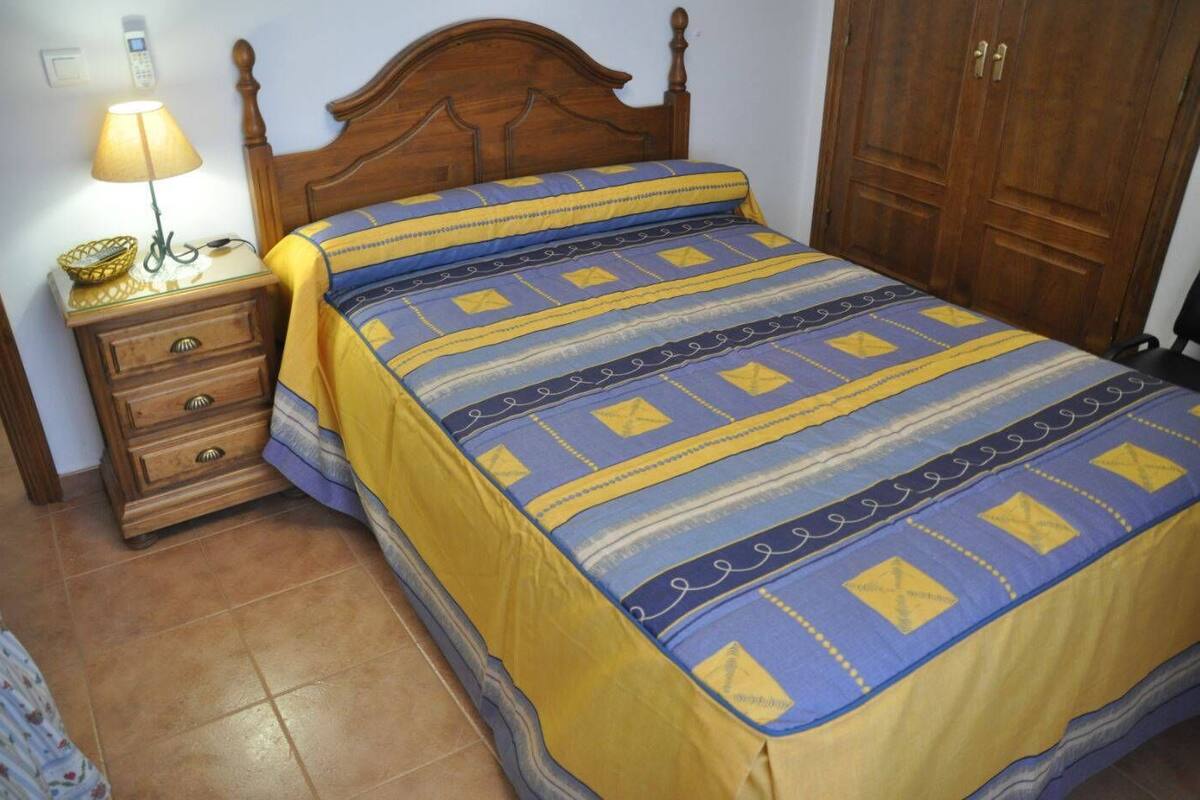 Ein Schlafzimmer mit einem hölzernen Bett, einem Nachttisch mit Lampe und einem Kleiderschrank.