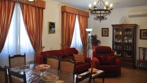 A living room with a dining table, two red sofas, a chandelier, and a cabinet with glassware. - Los galanes  (Villanueva de los Infantes)