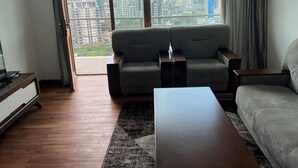 A modern living room with a sofa, a coffee table, and a view of a cityscape through large windows. - Delightful 3-bedroom apartment with best view in Addis Ababa (Addis Ababa)