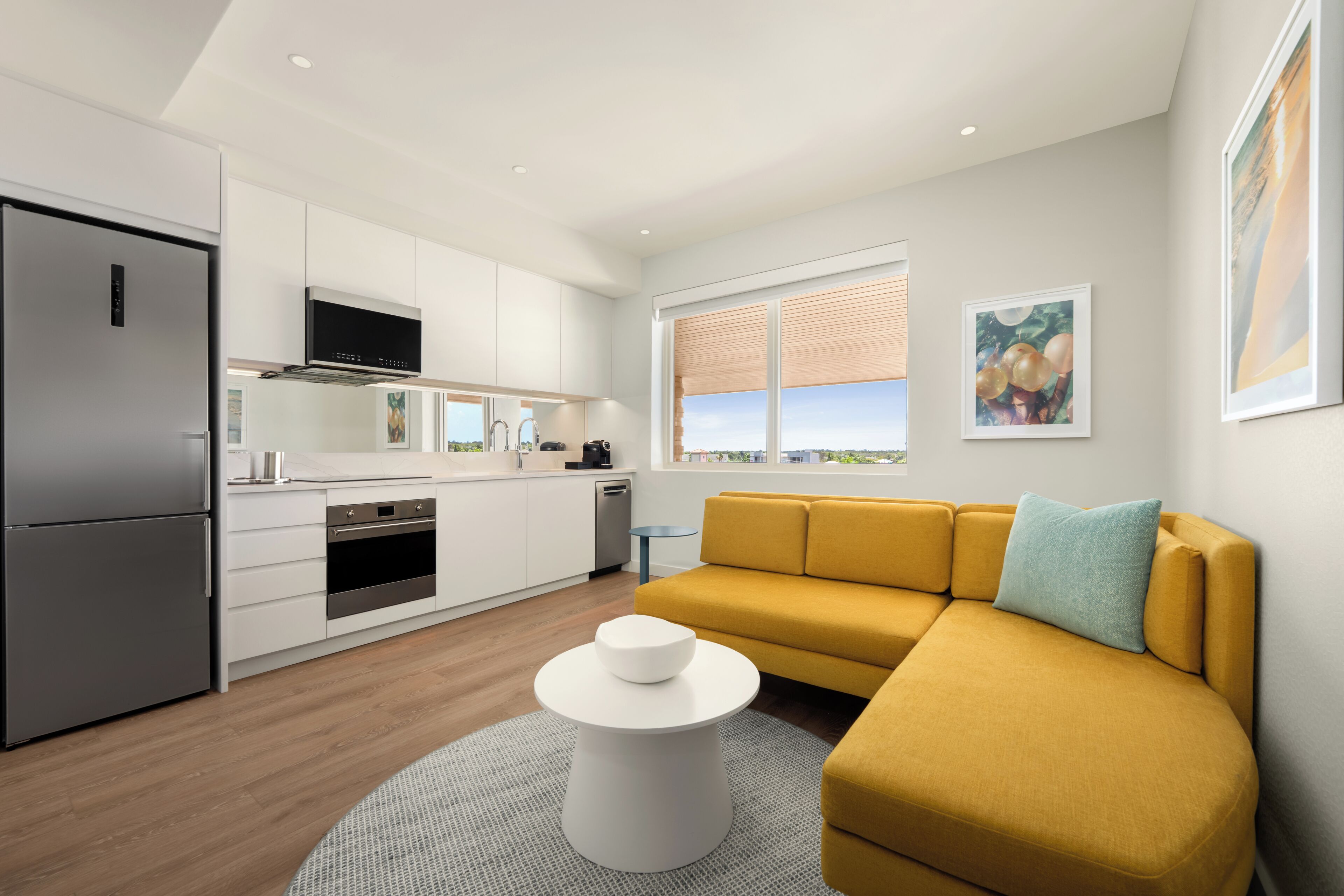 A modern kitchen with white cabinetry, a built-in oven, and a stainless steel refrigerator.
