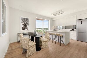Una cocina moderna con armarios blancos, una isla central y un amplio ventanal.