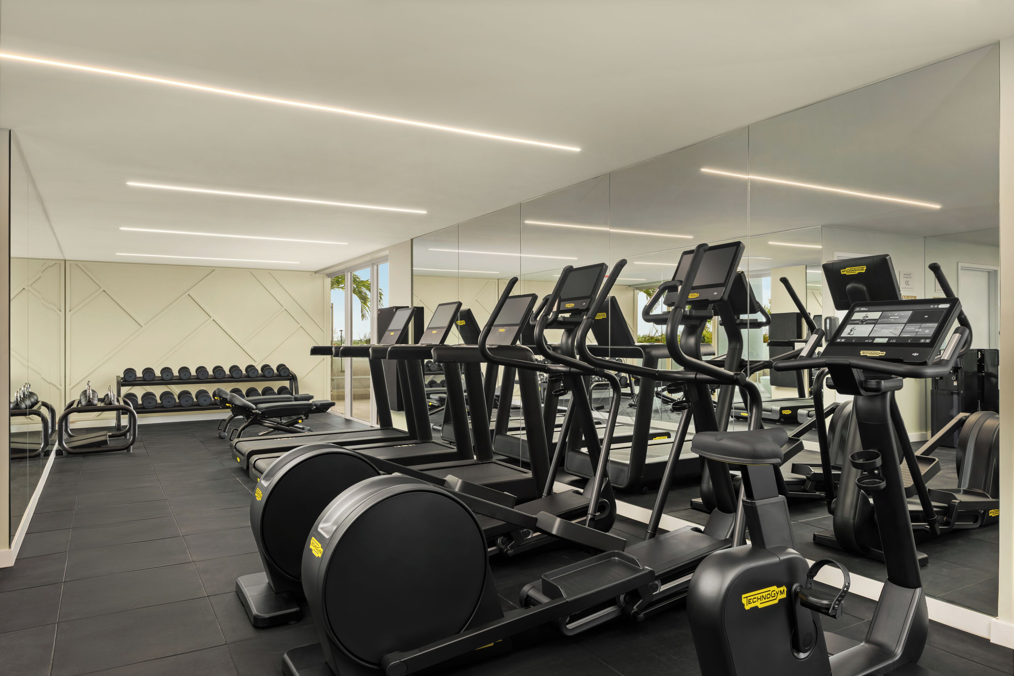 Un gimnasio con cintas de correr, elípticas y pesas sueltas.