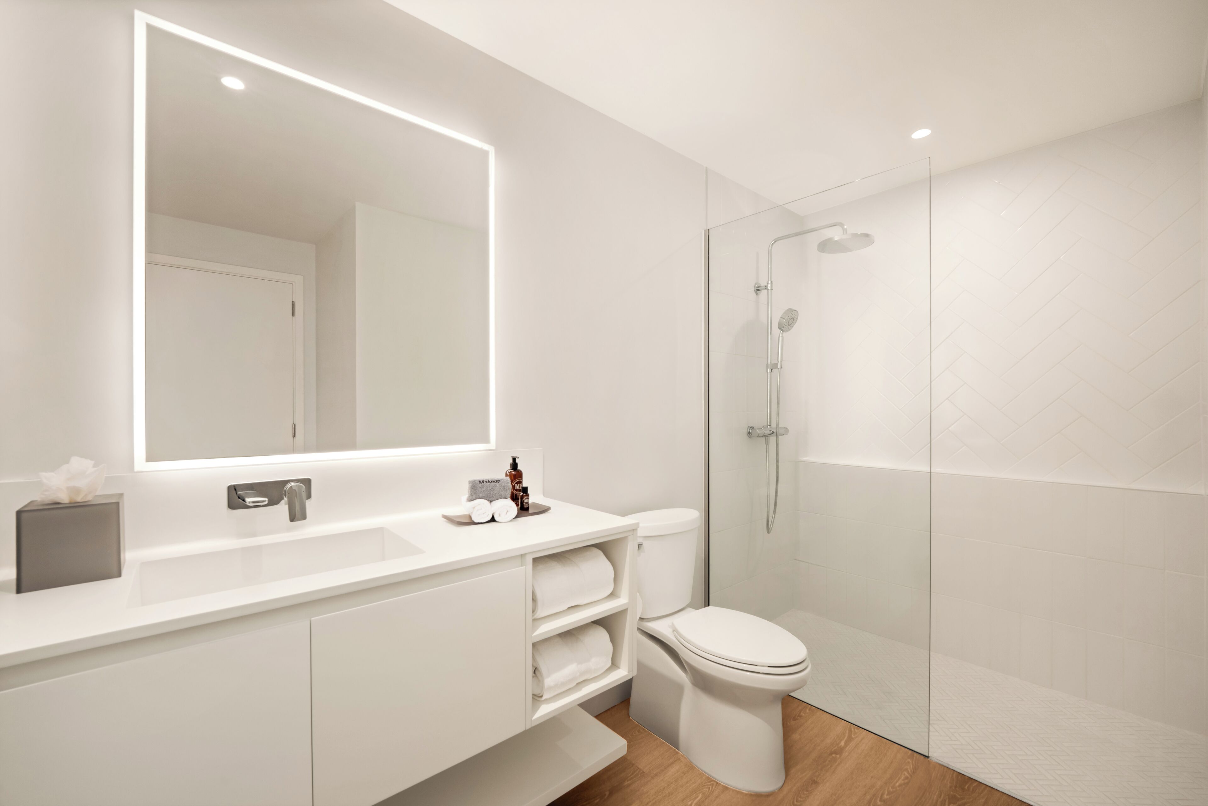 Un bagno moderno con uno specchio grande, un lavandino bianco, un water e una cabina doccia in vetro.