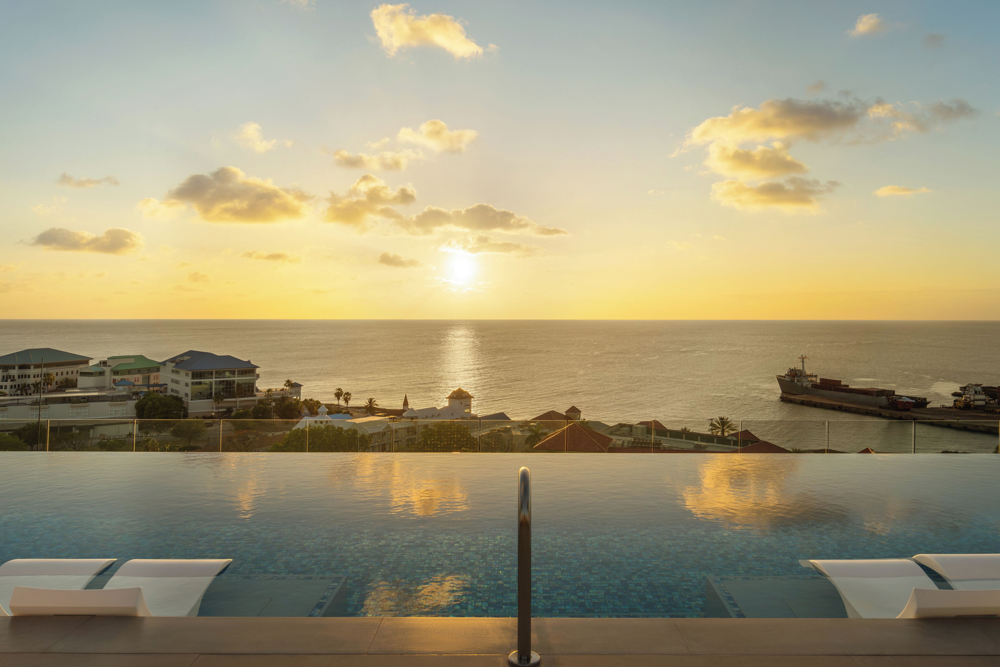 An infinity pool with a view of the ocean and a sunset.