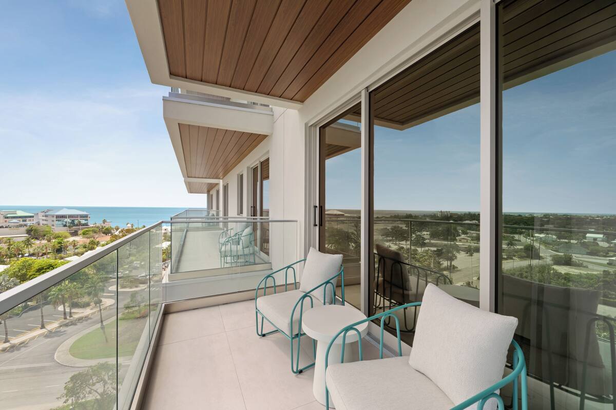 A balcony with two chairs and a table, overlooking a coastal view.