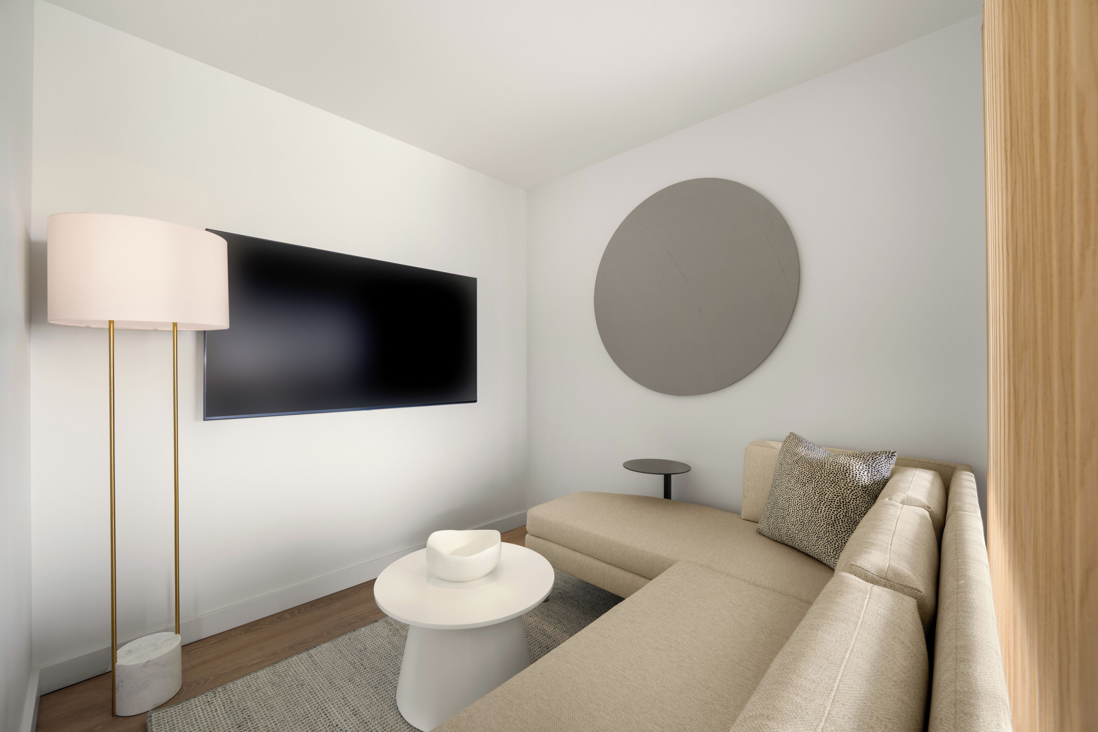 Un salon moderne avec un canapé, un élément de décoration murale rond, un téléviseur à écran plat et une lampe sur pied.