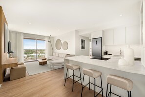 A modern kitchen with a central island, bar stools, and a large window.