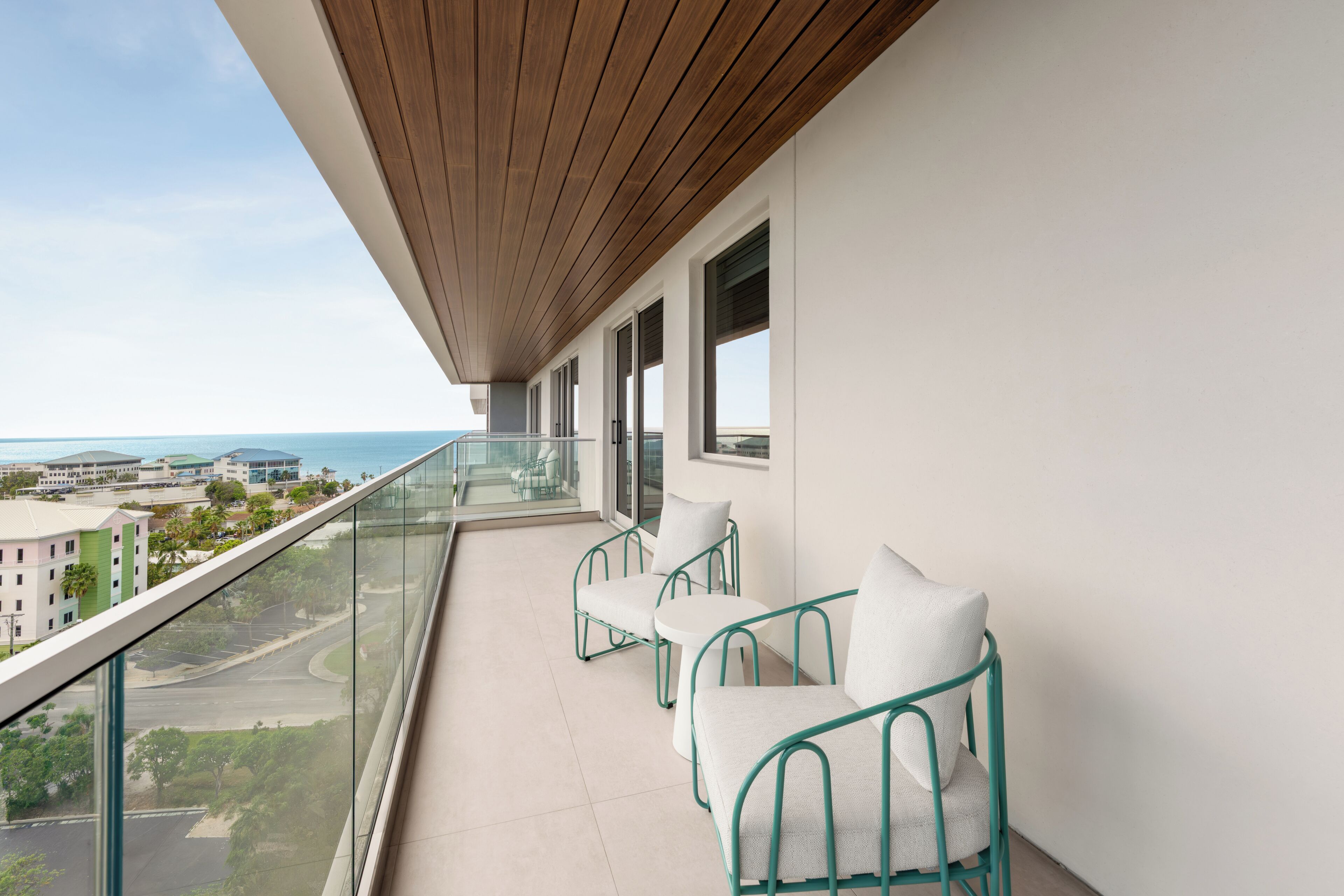 Un balcone con vista sull'oceano, due sedie e un tavolo.