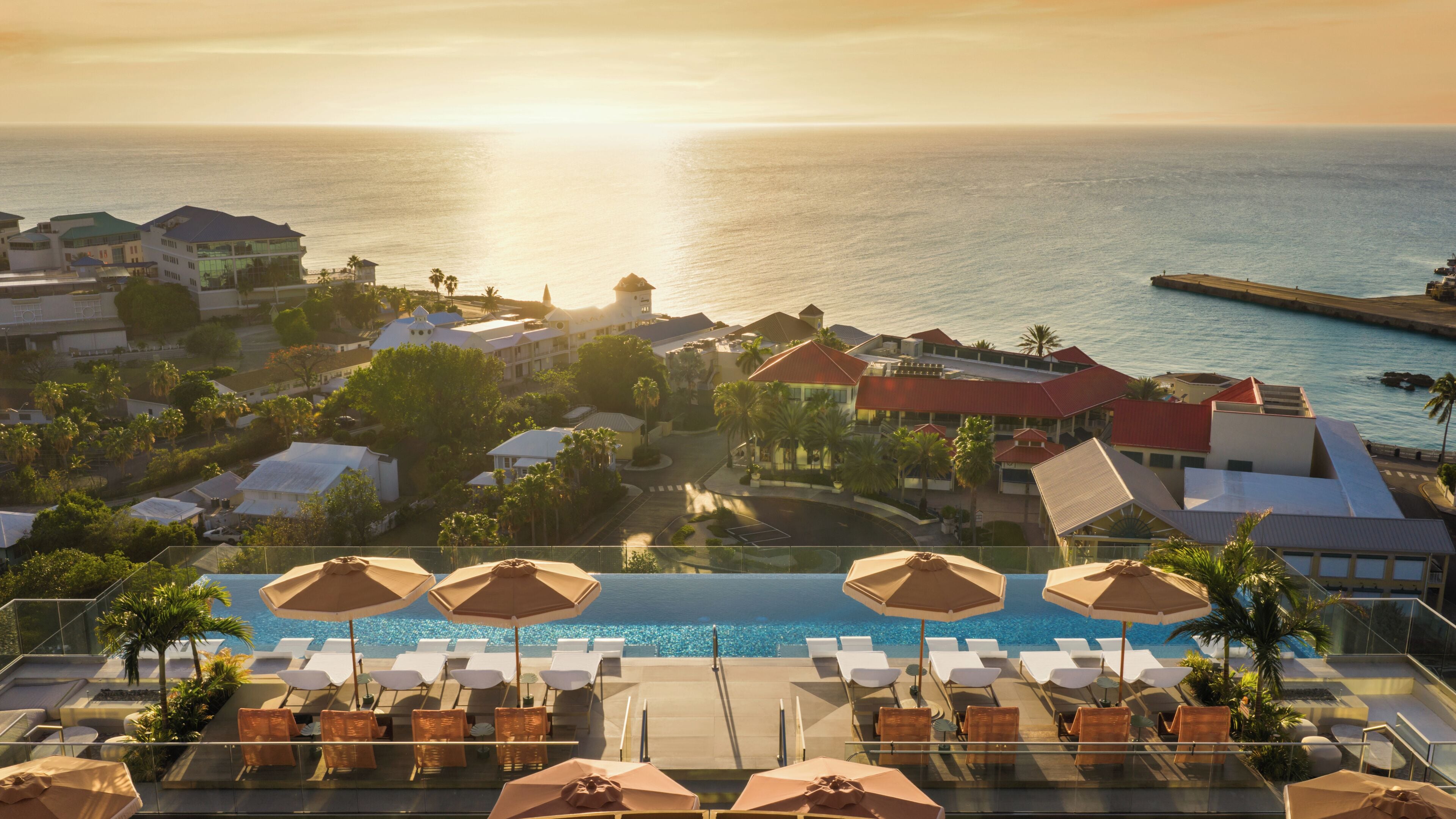 A resort with a pool, lounge chairs, and a view of the ocean.