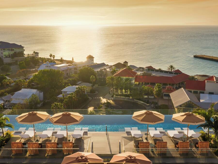 Un resort con piscina, sillas de descanso y vistas al océano.