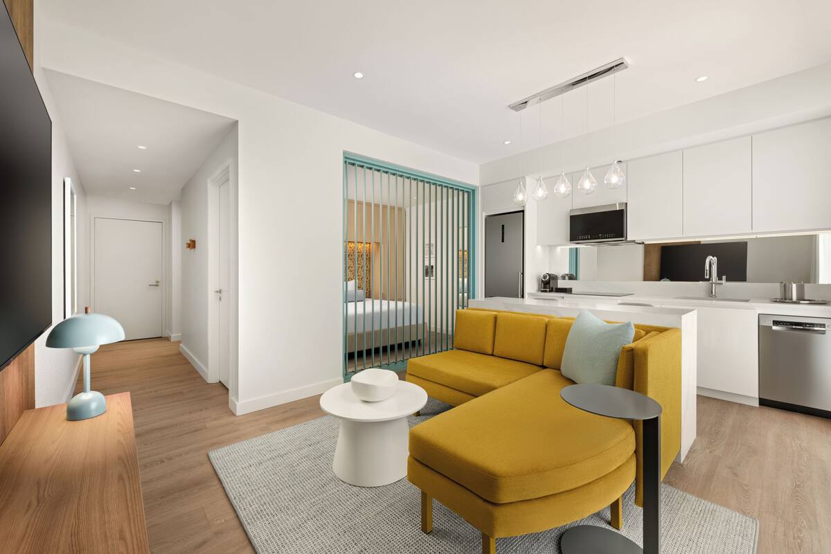 A modern apartment with a living area, kitchen, and a bedroom with a window.