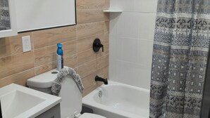 A bathroom with a toilet, sink, bathtub, and shower curtain. - Spacious 4-bedroom, 4 beds 2 bath each, in lovely Newark with AC, WiFi. (Newark)