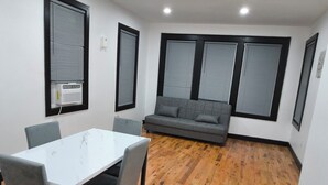 A room with a white table and chairs, a grey sofa, and a wooden floor. - Spacious 4-bedroom, 4 beds 2 bath each, in lovely Newark with AC, WiFi. (Newark)