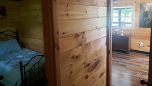 Een kamer met houten lambrisering, een bed, een dressoir en een schilderij aan de wand.