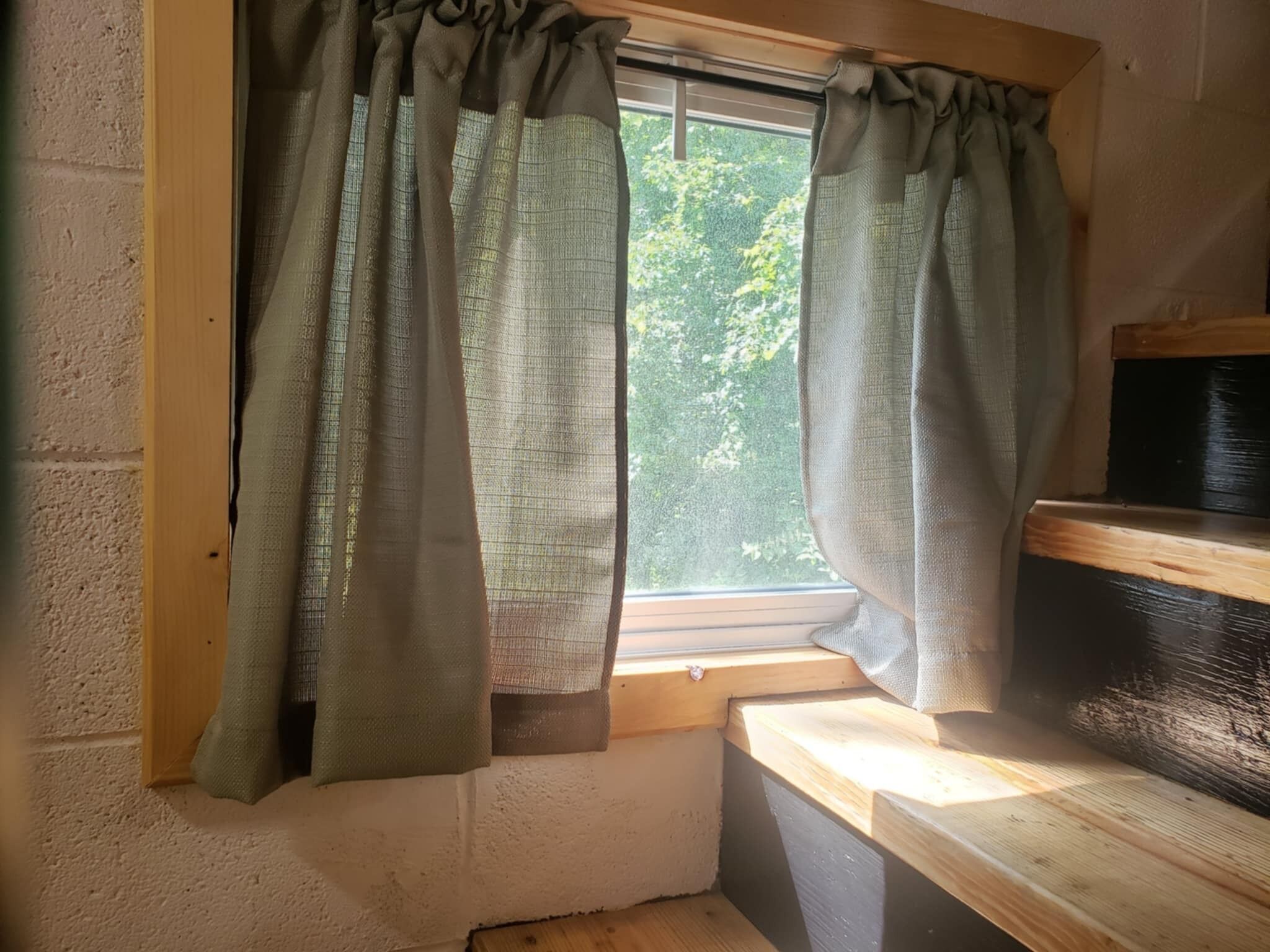 Une pièce avec une fenêtre, un banc en bois et un mur à la finition texturée.