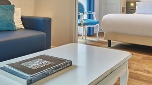 A hotel room with a bed, a desk with a book, a chair, and a mirror.