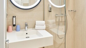 Een moderne badkamer met een douchecabine van glas, een wit wastafelmeubel met spiegel en een handdoekhouder.