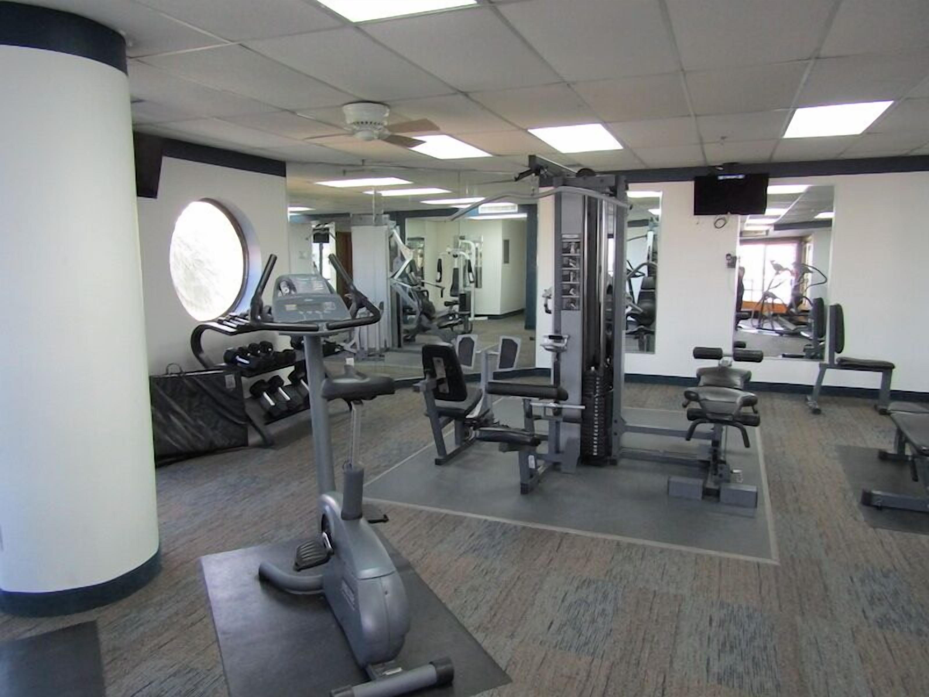 A gym with cardio machines, weightlifting equipment, and a mirror.