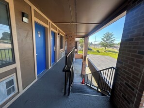 A covered walkway with blue doors, a metal staircase, and a view of a parking lot. - Mountain View Inn Irvine Near Richmond KY (Irvine)