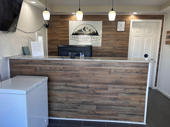 A reception desk with a wooden panel design, a sign reading 'Mountain View Inn,' and a door to the right.