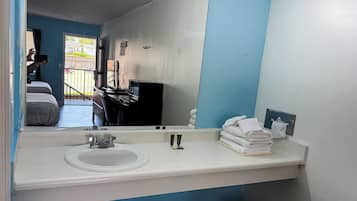 Une salle de bain avec un lavabo, un miroir et une pile de serviettes.