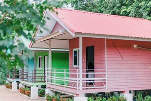 A row of colorful cabins with a red roof, green and blue exteriors, and a white porch railing. - Chalalai Resort Kham Chanot By Zuzu (Ban Dung)