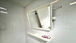 A bathroom with a white tiled wall, a mirror, and a shelf with toiletries. - Chalalai Resort Kham Chanot By Zuzu (Ban Dung)