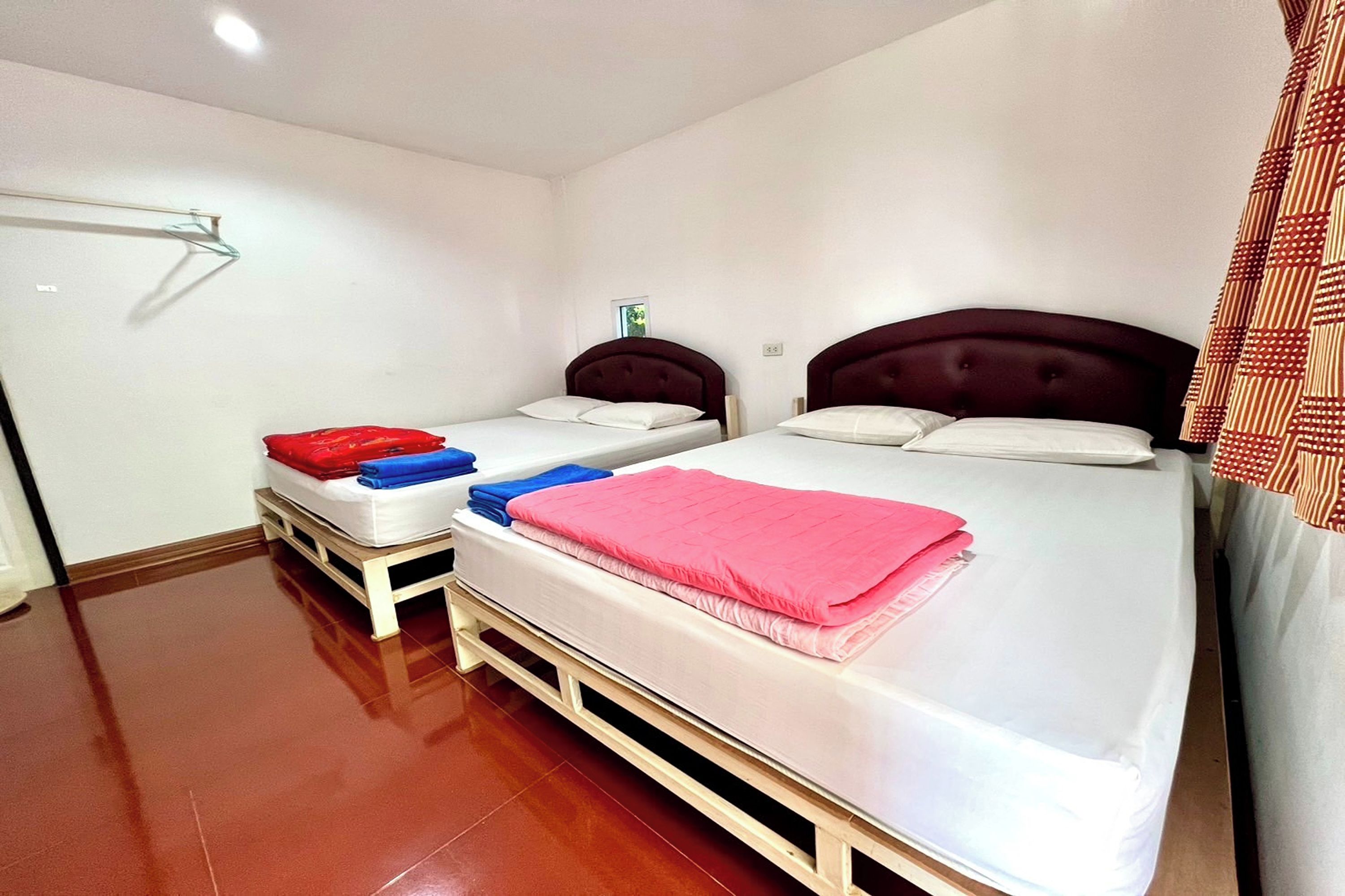 A hotel room with two beds, each with a headboard, and a wooden floor.