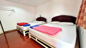 A hotel room with two beds, each with a headboard, and a wooden floor.