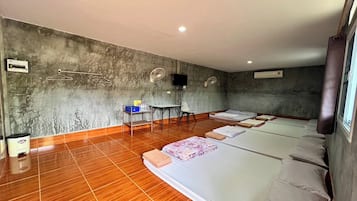 A hotel room with a large bed, a small desk, a chair, and a television on the wall.