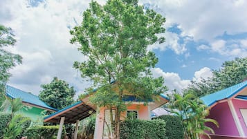A building with a blue roof, surrounded by greenery and a clear sky.