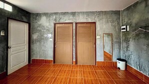 A room with two wooden doors, a tiled floor, a wall-mounted mirror, and a trash bin.