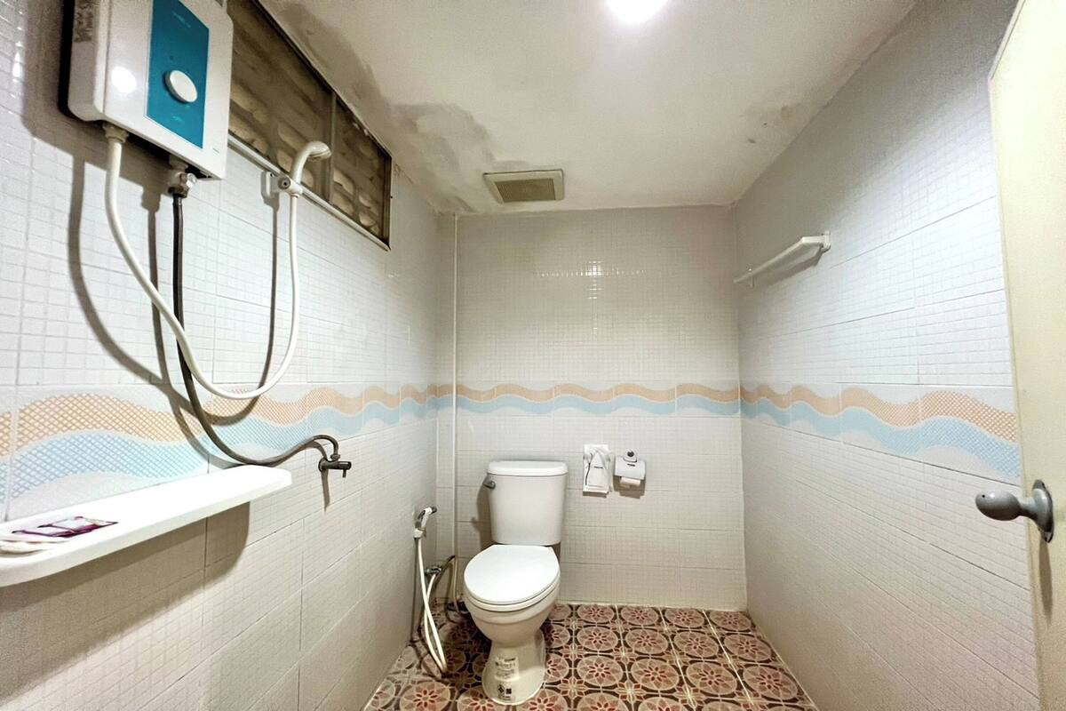 A small, tiled bathroom with a toilet, a shower, and a sink.