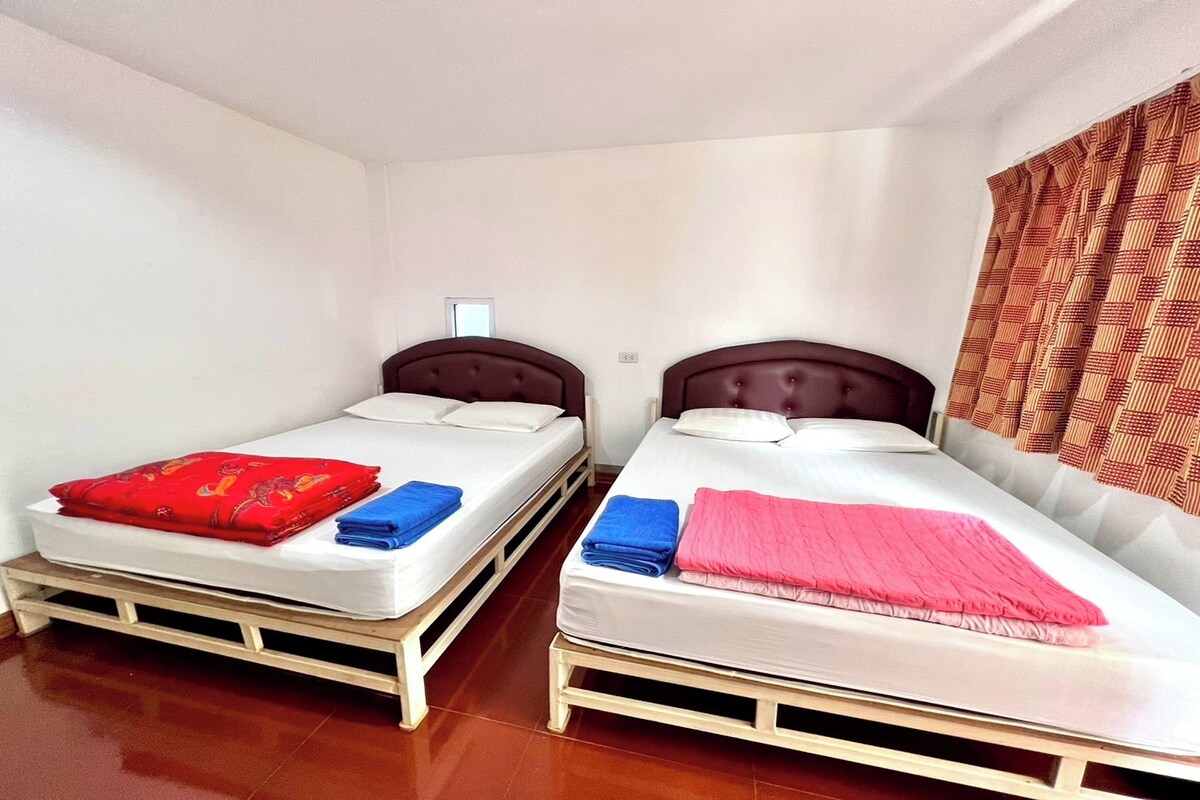 Two single beds with headboards, white bedding, and a red and blue blanket on the left bed.