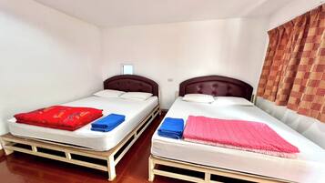 Two single beds with headboards, white bedding, and a red and blue blanket on the left bed.