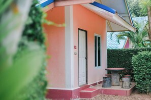 A small building with a red and white exterior, a door, and a small outdoor seating area with a table and stools. - Chalalai Resort Kham Chanot By Zuzu (Ban Dung)