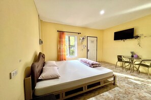 A bedroom with a bed, a desk, a chair, a television, and a window with curtains. - Chalalai Resort Kham Chanot By Zuzu (Ban Dung)