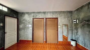 A room with two wooden doors, a tiled floor, a wall-mounted mirror, and a trash bin.